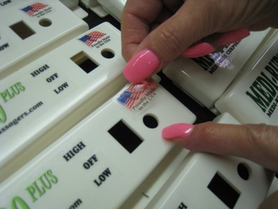 A person with pink nails carefully applies a sticker onto a massager