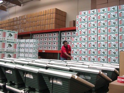 A Man Stands In Front Of A Warehouse Filled With Massager Boxes